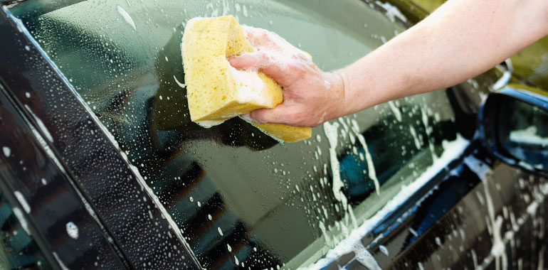 Tvättar bil med svamp.