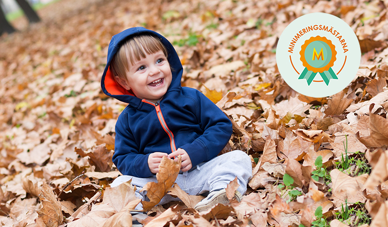 Ett barn ler lyckligt i höstlöv, på bilden ligger Minimeringsmästarnas logotyp.
